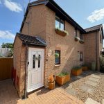 Brick house with white door and flower boxes.