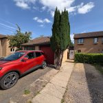 Red car parked in front of suburban house.