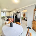 Modern kitchen and dining area with flowers on table.