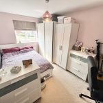 Cosy bedroom with desk, guitar, and wardrobe.