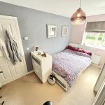 Bright bedroom with double bed and patterned duvet.