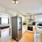 Modern kitchen with wooden floor and stainless appliances.
