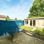 Sunny garden with patio and wooden shed.