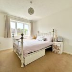 Bright bedroom with metal bed and wooden furniture.