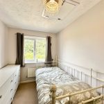 Cosy bedroom with white bed and dresser.