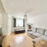 Bright, modern living room with grey sofa, wooden floor.