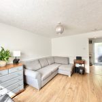 Modern living room with grey sofa and wooden furniture.