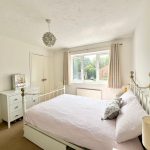Bright bedroom with double bed and window view.