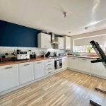 Modern kitchen with white cabinets and treadmill.