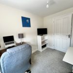 Modern home office with desk, chair, and laptops.