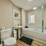 Modern bathroom with bath, shower, sink, and toilet.