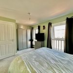 Bright bedroom with bed, wardrobe, window and curtains.