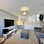 Modern living room with grey sofa and large TV.