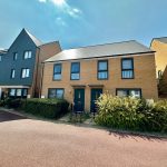Modern UK terraced houses under blue sky.