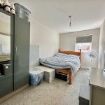 Small bedroom with bed, wardrobe, and fan.