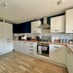 Modern kitchen with white cabinets and wooden worktops.