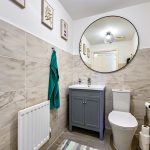 Modern bathroom with mirror and tiled walls.