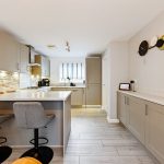 Modern kitchen with breakfast bar and grey cabinets.