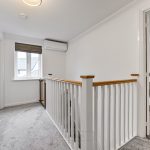 Bright upstairs hallway with railing and window.