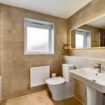 Modern beige bathroom with sink, toilet, and mirror.