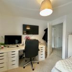 Spacious office with desk, chair, monitors and shelves.