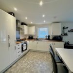 Modern kitchen with dining table and appliances.