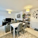 Modern living room with dining area and large clock.