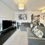 Modern living room with grey sofa and wall clock.