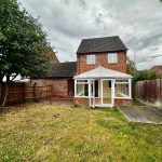 Back garden with brick house and conservatory.