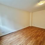Empty room with wooden floor and light walls.