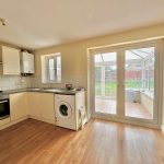 Modern kitchen with washing machine and patio doors.
