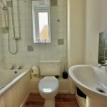 Small bathroom with bathtub, toilet and sink.