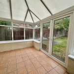 Bright conservatory with glass doors to garden.