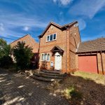 Two-storey brick house with garage, sunny day.