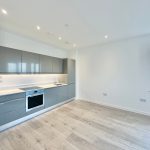 Modern kitchen with grey cabinets and wooden floor.