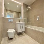 Modern beige bathroom with bathtub and toilet.