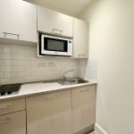 Compact kitchen with microwave and electric hob.
