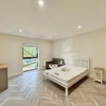 Bright bedroom with bed, sofa, desk, and window.