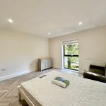 Bright bedroom with bed, sofa, window view.