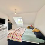 Loft bedroom with bed, TV, and stuffed toy.