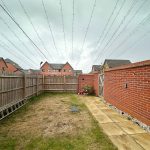 Back garden with string lights and red brick wall.