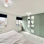 Bright bedroom with mirrored green wardrobes.