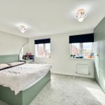 Modern bedroom with green accents and natural light.