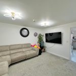 Living room with beige sofa and wall-mounted TV.