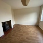 Unfurnished room with wood floor and stove.