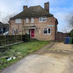 Semi-detached brick house with red door, UK.