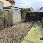 Empty backyard with gravel and wooden fence.