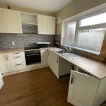 Modern kitchen with white cabinets and tiled splashback.