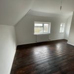 Empty room with wooden floor and white walls.
