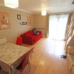 Spacious living room with red sofa and dining table.